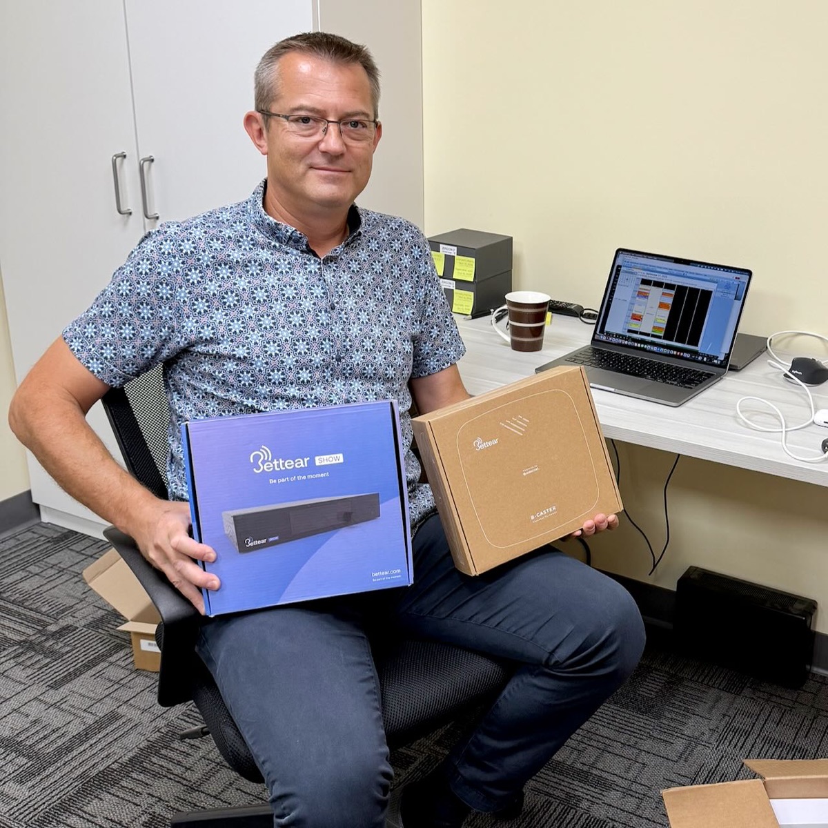 Martin Jurek at the clinic holding the Bettear and Auracast equipment boxes